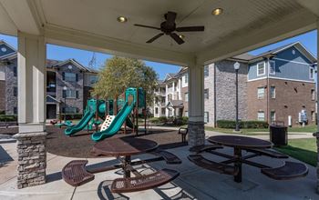 Covered patio with tables and chairs and playground equipment